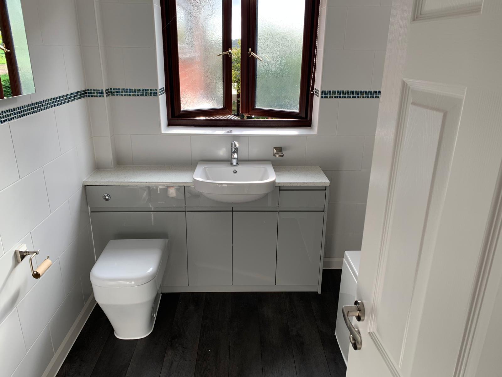 A finished bathroom with a grey fitted vanity unit, basin and back-to-wall toilet